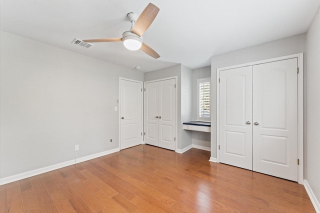 10714 Deerwood Rd, Houston, TX 77042 - unfurnished bedroom featuring two closets, light wood-type flooring, and a ceiling fan