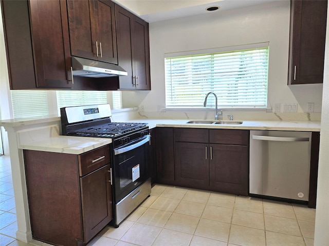 3307 Twelve Oaks Ln, Missouri City, TX 77459 - kitchen featuring appliances with stainless steel finishes, under cabinet range hood, dark brown cabinets, light tile patterned flooring, and light countertops