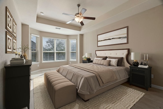 2206 Wolf Creek Ct, Katy, TX 77493 - bedroom with baseboards, wood finished floors, a tray ceiling, and ceiling fan