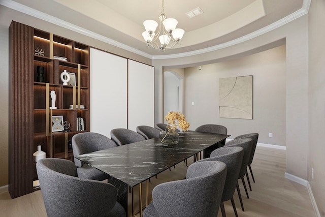 2206 Wolf Creek Ct, Katy, TX 77493 - dining area featuring a chandelier, ornamental molding, baseboards, light wood-style flooring, and a tray ceiling