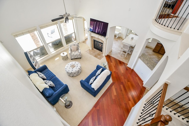 19707 Mission Pines Ln, Richmond, TX 77407 - living room featuring a high ceiling, a premium fireplace, arched walkways, ceiling fan, and wood finished floors