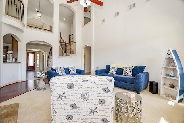 19707 Mission Pines Ln, Richmond, TX 77407 - living area featuring carpet floors, a high ceiling, stairs, a ceiling fan, and arched walkways