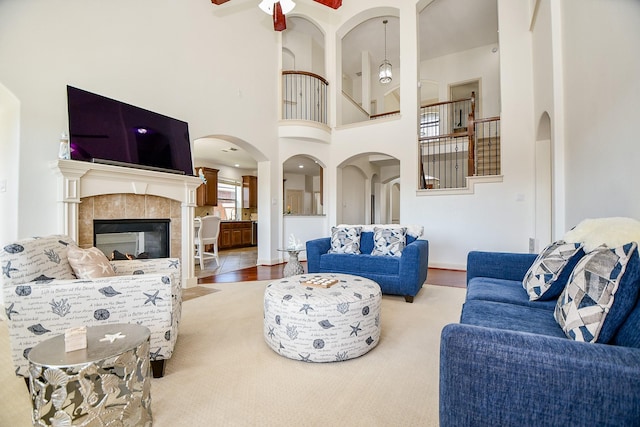 19707 Mission Pines Ln, Richmond, TX 77407 - living area featuring a ceiling fan, a high ceiling, a tiled fireplace, and arched walkways
