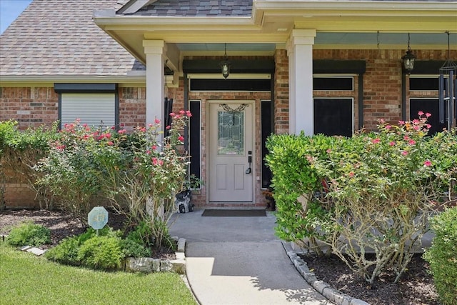 4810 Majestic Dr, Baytown, TX 77523 - doorway to property featuring a shingled roof, brick siding, and a porch