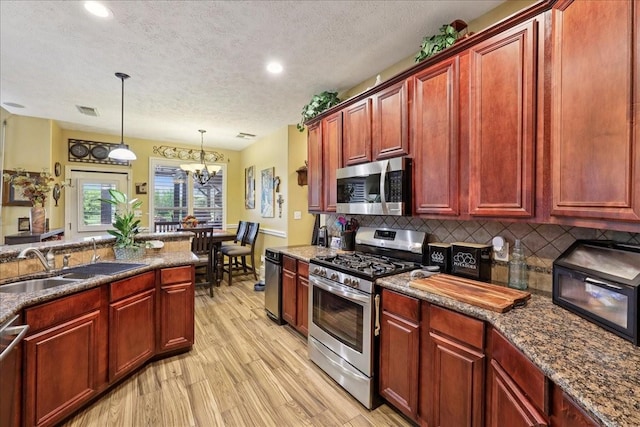 4810 Majestic Dr, Baytown, TX 77523 - kitchen with stainless steel appliances, dark brown cabinets, decorative backsplash, a textured ceiling, and a chandelier
