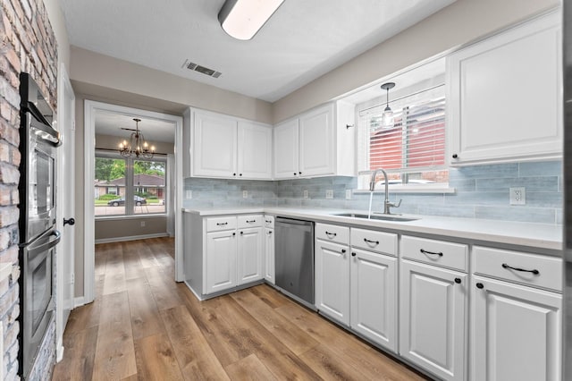 9407 Brooding Oak Cir, Houston, TX 77096 - kitchen with a sink, appliances with stainless steel finishes, a chandelier, white cabinets, and light countertops