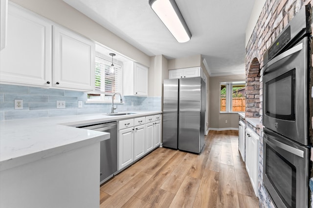 9407 Brooding Oak Cir, Houston, TX 77096 - kitchen with stainless steel appliances, a sink, light wood-style flooring, white cabinets, and tasteful backsplash