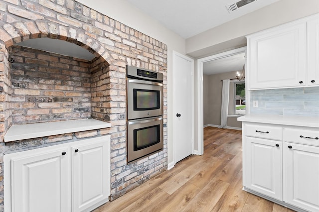 9407 Brooding Oak Cir, Houston, TX 77096 - kitchen with double oven, white cabinetry, light wood-style flooring, a chandelier, and light countertops