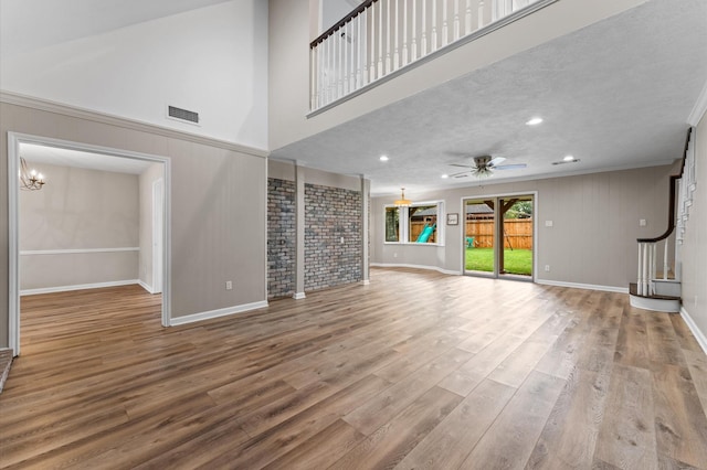 9407 Brooding Oak Cir, Houston, TX 77096 - unfurnished living room with baseboards, wood finished floors, a ceiling fan, ornamental molding, and a towering ceiling