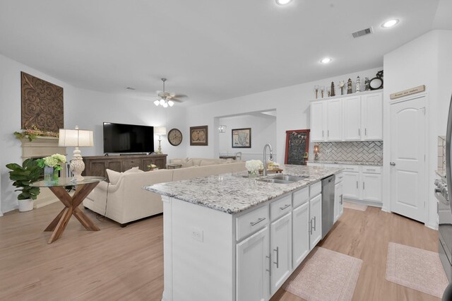16220 Fayette St, Conroe, TX 77303 - kitchen featuring a sink, stainless steel dishwasher, white cabinets, light wood-style flooring, and a center island with sink
