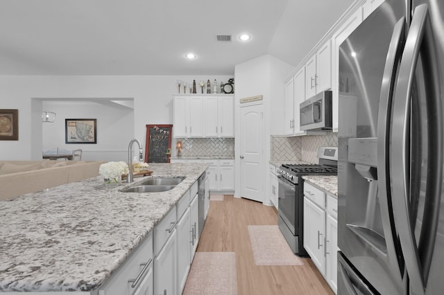16220 Fayette St, Conroe, TX 77303 - kitchen with appliances with stainless steel finishes, a sink, light wood-style floors, white cabinets, and recessed lighting