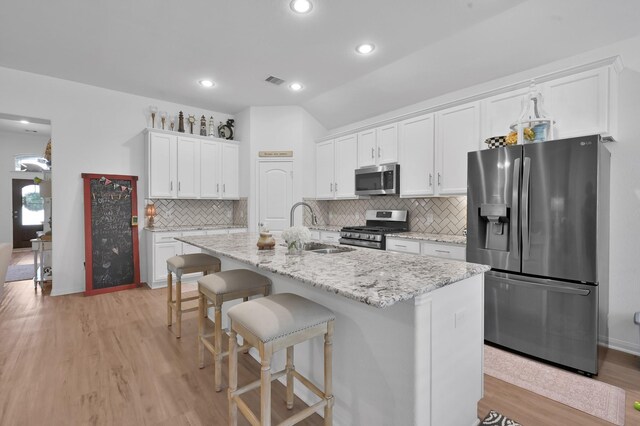 16220 Fayette St, Conroe, TX 77303 - kitchen with appliances with stainless steel finishes, a sink, light wood-style floors, white cabinetry, and a center island with sink