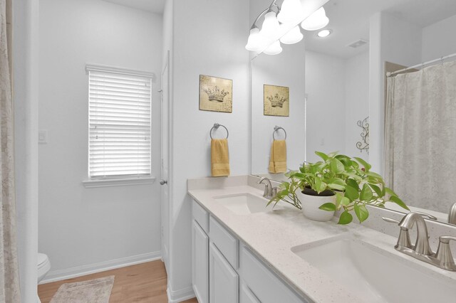 16220 Fayette St, Conroe, TX 77303 - full bathroom with double vanity, toilet, wood finished floors, and baseboards