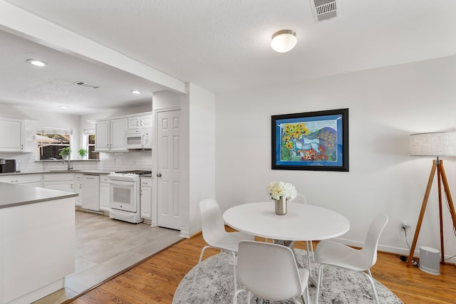 3923 W Main St, Houston, TX 77027 - dining room featuring recessed lighting, light wood-style floors, baseboards, and a textured ceiling