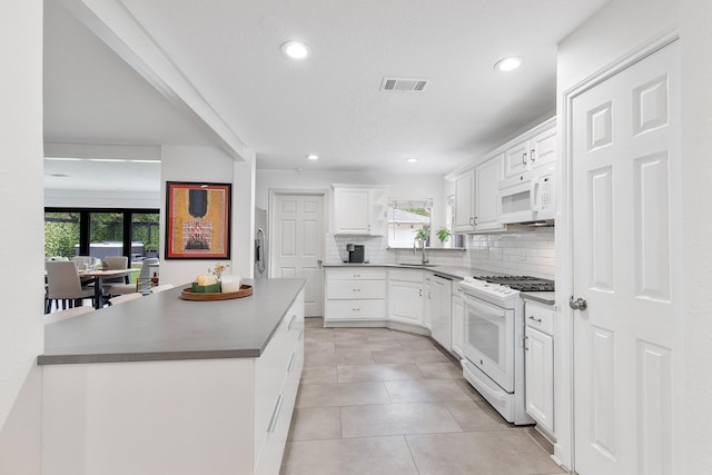 3923 W Main St, Houston, TX 77027 - kitchen featuring white appliances, backsplash, white cabinets, a sink, and recessed lighting