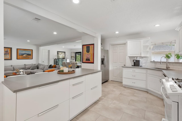 3923 W Main St, Houston, TX 77027 - kitchen featuring stainless steel fridge, stove, a sink, white cabinets, and recessed lighting