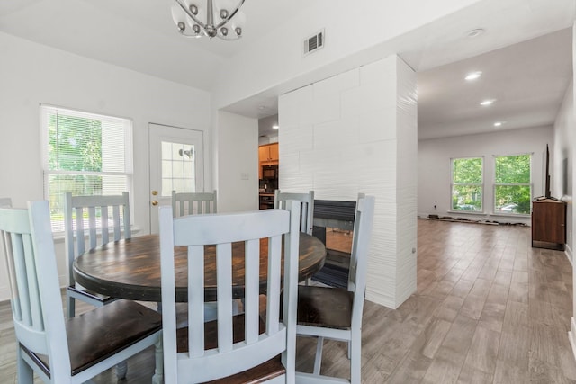 4313 Windswept Dr, Montgomery, TX 77356 - dining area with light wood-style flooring, a chandelier, recessed lighting, and a tiled fireplace