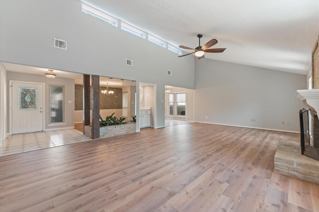 15914 Alta Mesa Dr, Houston, TX 77083 - unfurnished living room featuring a fireplace, ceiling fan, a chandelier, a high ceiling, and light wood-style flooring