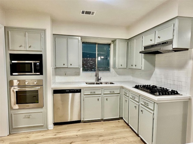 22906 Lemon Grove Dr, Spring, TX 77373 - kitchen featuring stainless steel appliances, gray cabinets, backsplash, and light wood-style floors