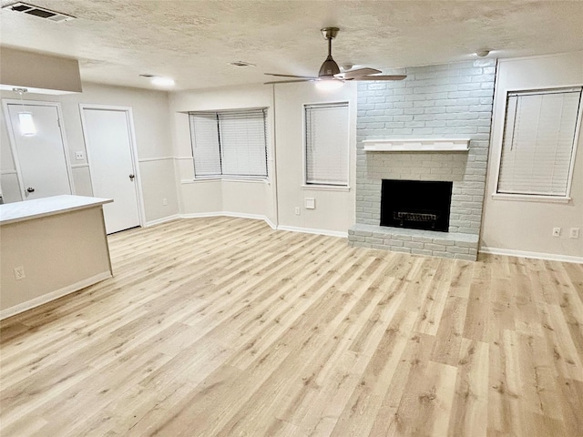 22906 Lemon Grove Dr, Spring, TX 77373 - unfurnished living room with a ceiling fan, light wood-style floors, a textured ceiling, and a brick fireplace