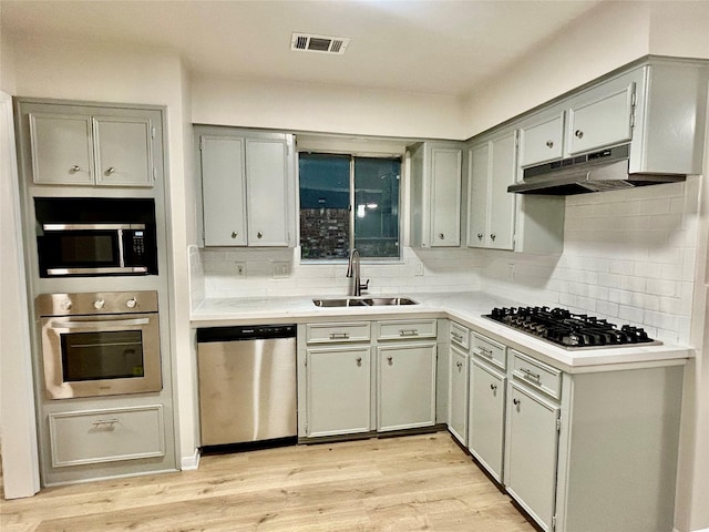 22906 Lemon Grove Dr, Spring, TX 77373 - kitchen with appliances with stainless steel finishes, gray cabinetry, tasteful backsplash, and light wood-style flooring