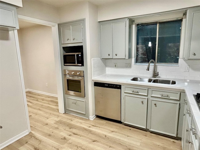 22906 Lemon Grove Dr, Spring, TX 77373 - kitchen with stainless steel appliances, gray cabinetry, light wood-style floors, backsplash, and light countertops