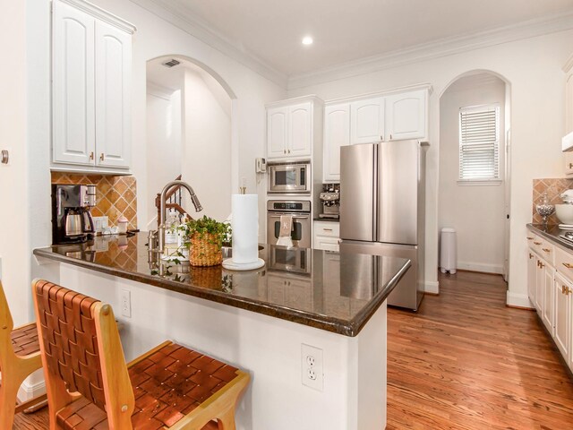 4133 Dickson St, Houston, TX 77007 - kitchen with appliances with stainless steel finishes, arched walkways, a peninsula, tasteful backsplash, and crown molding