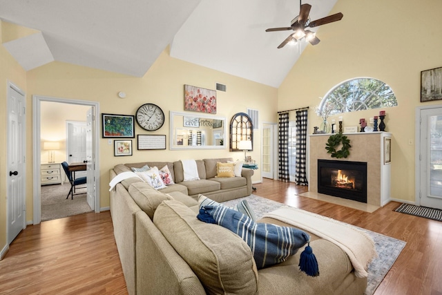 3233 Greenhead St, Katy, TX 77493 - living area with a tiled fireplace, light wood-style floors, a ceiling fan, high vaulted ceiling, and baseboards