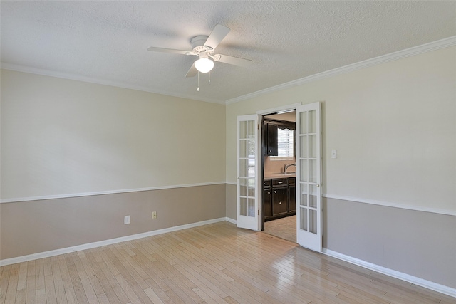 5411 Mossy Timbers Dr, Humble, TX 77346 - empty room with french doors, a ceiling fan, light wood finished floors, a textured ceiling, and crown molding