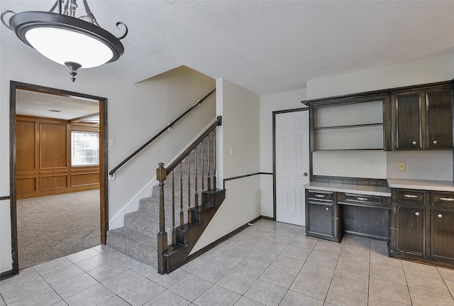 5411 Mossy Timbers Dr, Humble, TX 77346 - kitchen with light tile patterned flooring, light countertops, a textured ceiling, dark brown cabinets, and open shelves