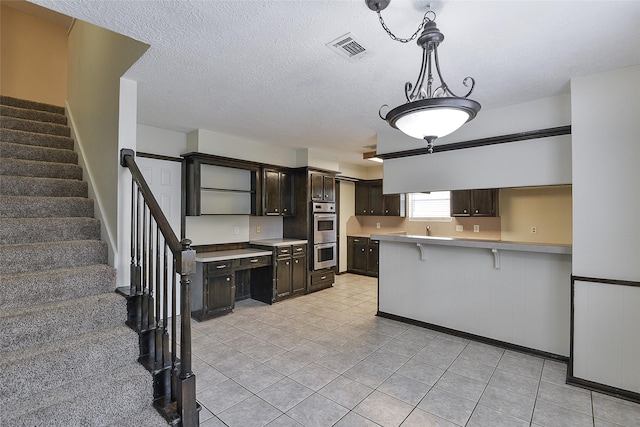 5411 Mossy Timbers Dr, Humble, TX 77346 - kitchen with dark brown cabinetry, light countertops, light tile patterned flooring, a kitchen bar, and stainless steel double oven