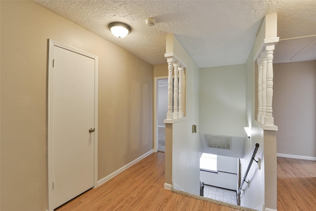 5411 Mossy Timbers Dr, Humble, TX 77346 - corridor featuring wood finished floors, a textured ceiling, an upstairs landing, and decorative columns