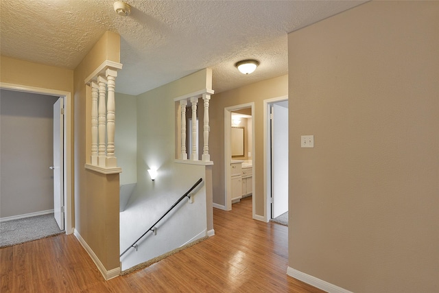 5411 Mossy Timbers Dr, Humble, TX 77346 - hallway with an upstairs landing, wood finished floors, a textured ceiling, and ornate columns