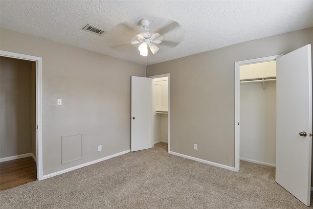 5411 Mossy Timbers Dr, Humble, TX 77346 - unfurnished bedroom with light colored carpet, a walk in closet, a ceiling fan, and a textured ceiling