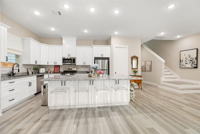4926 Wunder Way, Houston, TX 77069 - kitchen featuring stainless steel appliances, a sink, a center island, white cabinets, and backsplash