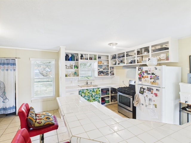 1429 S Mathis St, Rockport, TX 78382 - kitchen with stainless steel range with gas cooktop, open shelves, freestanding refrigerator, a sink, and tile counters