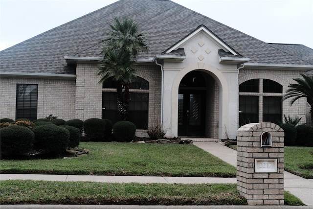 2217 W Reata Dr, Deer Park, TX 77536 - french country style house with french doors, a shingled roof, a front yard, and brick siding