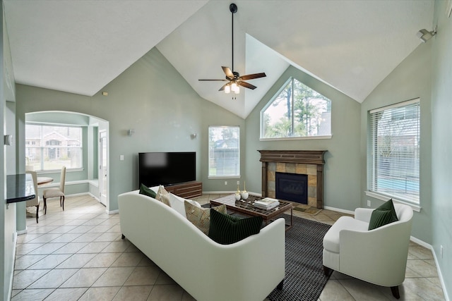 14522 Belvan Ct, Cypress, TX 77429 - living room featuring arched walkways, a tile fireplace, a ceiling fan, light tile patterned floors, and baseboards