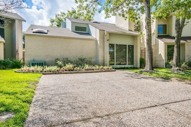 923 Cranberry Hill Ct, Houston, TX 77079 - mid-century modern home featuring brick siding, a chimney, a front lawn, cooling unit, and a patio