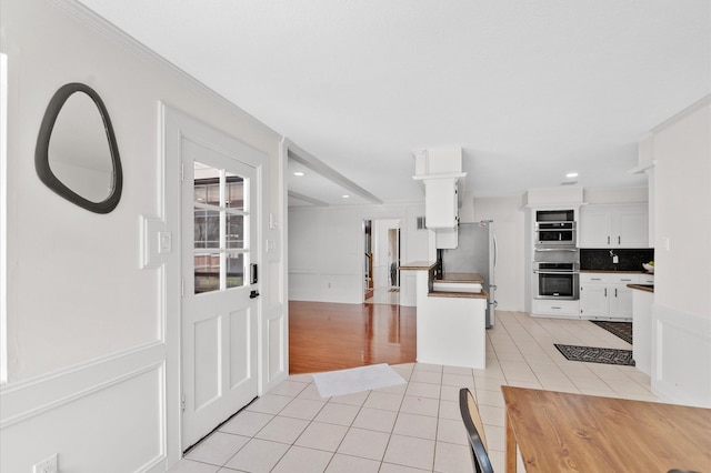 3602 Highland Lakes Dr, Kingwood, TX 77339 - kitchen with stainless steel oven, light tile patterned flooring, freestanding refrigerator, white cabinetry, and recessed lighting