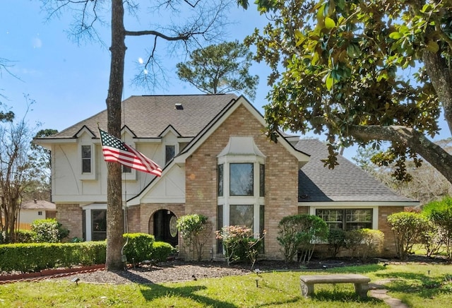 3602 Highland Lakes Dr, Kingwood, TX 77339 - tudor-style house featuring a shingled roof, brick siding, and a front yard