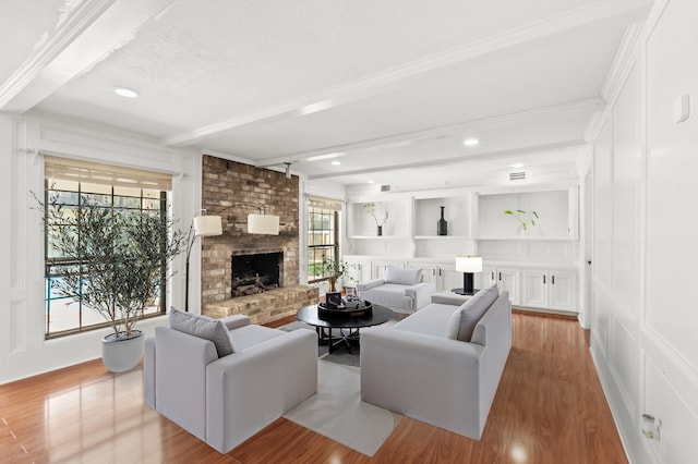 3602 Highland Lakes Dr, Kingwood, TX 77339 - living area featuring beamed ceiling, a decorative wall, light wood finished floors, a fireplace, and ornamental molding