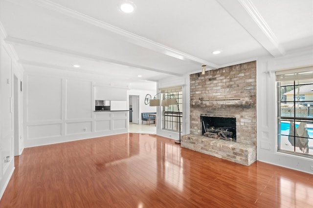 3602 Highland Lakes Dr, Kingwood, TX 77339 - unfurnished living room featuring beam ceiling, wood finished floors, a brick fireplace, and ornamental molding