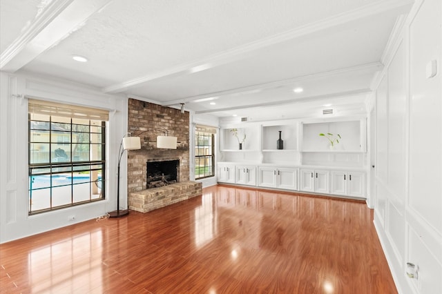 3602 Highland Lakes Dr, Kingwood, TX 77339 - unfurnished living room featuring beamed ceiling, wood finished floors, a textured ceiling, crown molding, and a brick fireplace