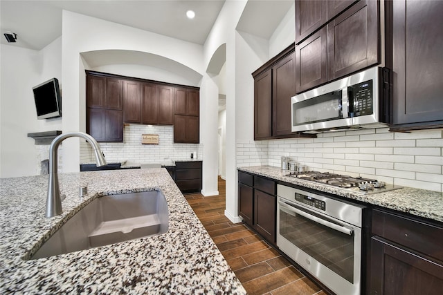 16711 Ramsay Cascades Dr, Humble, TX 77346 - kitchen featuring stainless steel appliances, a sink, light stone counters, dark wood finished floors, and dark brown cabinets