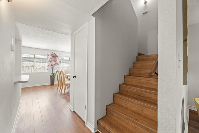 8101 Amelia Rd Unit 106, Houston, TX 77055 - staircase featuring baseboards, wood finished floors, and a textured ceiling