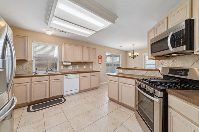 8123 Solara Bnd, Houston, TX 77083 - kitchen with appliances with stainless steel finishes, a sink, decorative backsplash, a chandelier, and a peninsula