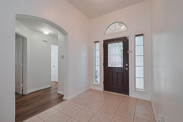 19826 Imperial Stone Dr, Houston, TX 77073 - foyer entrance featuring arched walkways, light tile patterned floors, baseboards, and healthy amount of natural light