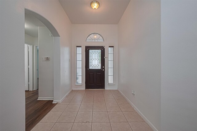 19826 Imperial Stone Dr, Houston, TX 77073 - foyer entrance with arched walkways, baseboards, and light tile patterned flooring