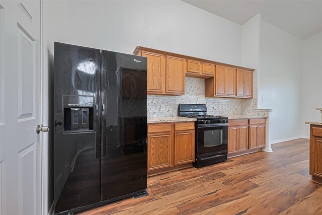 19826 Imperial Stone Dr, Houston, TX 77073 - kitchen with black appliances, backsplash, dark wood-style floors, brown cabinetry, and baseboards